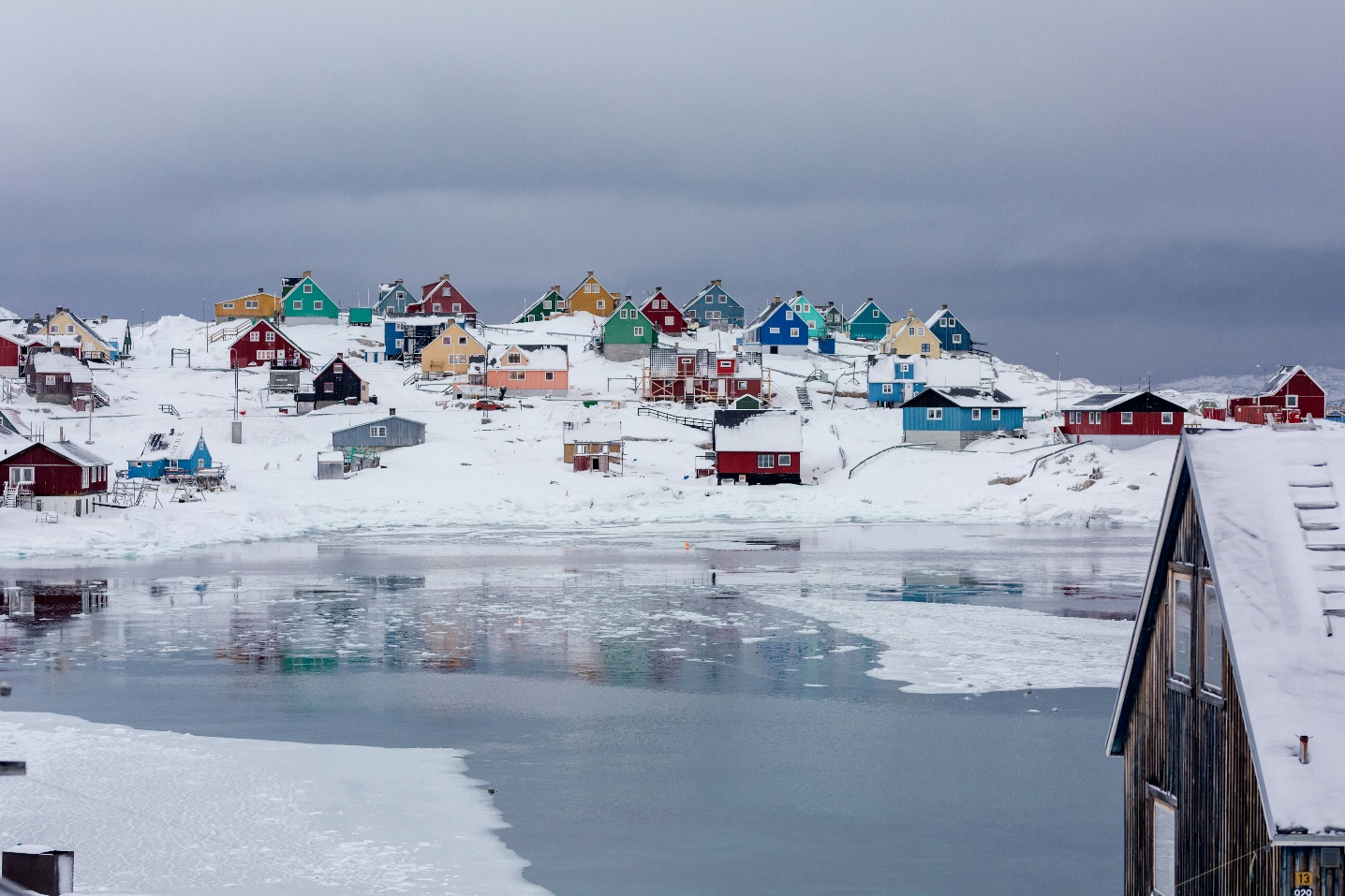 A group of colorful houses on a snowy hill

Description automatically generated